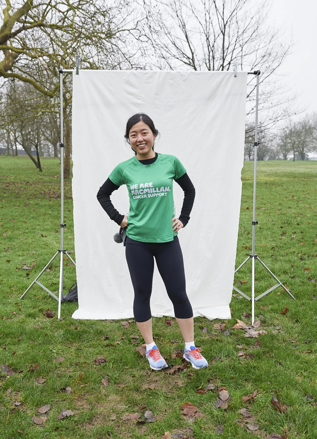 A smiling lady stands for a photo after running in the park
