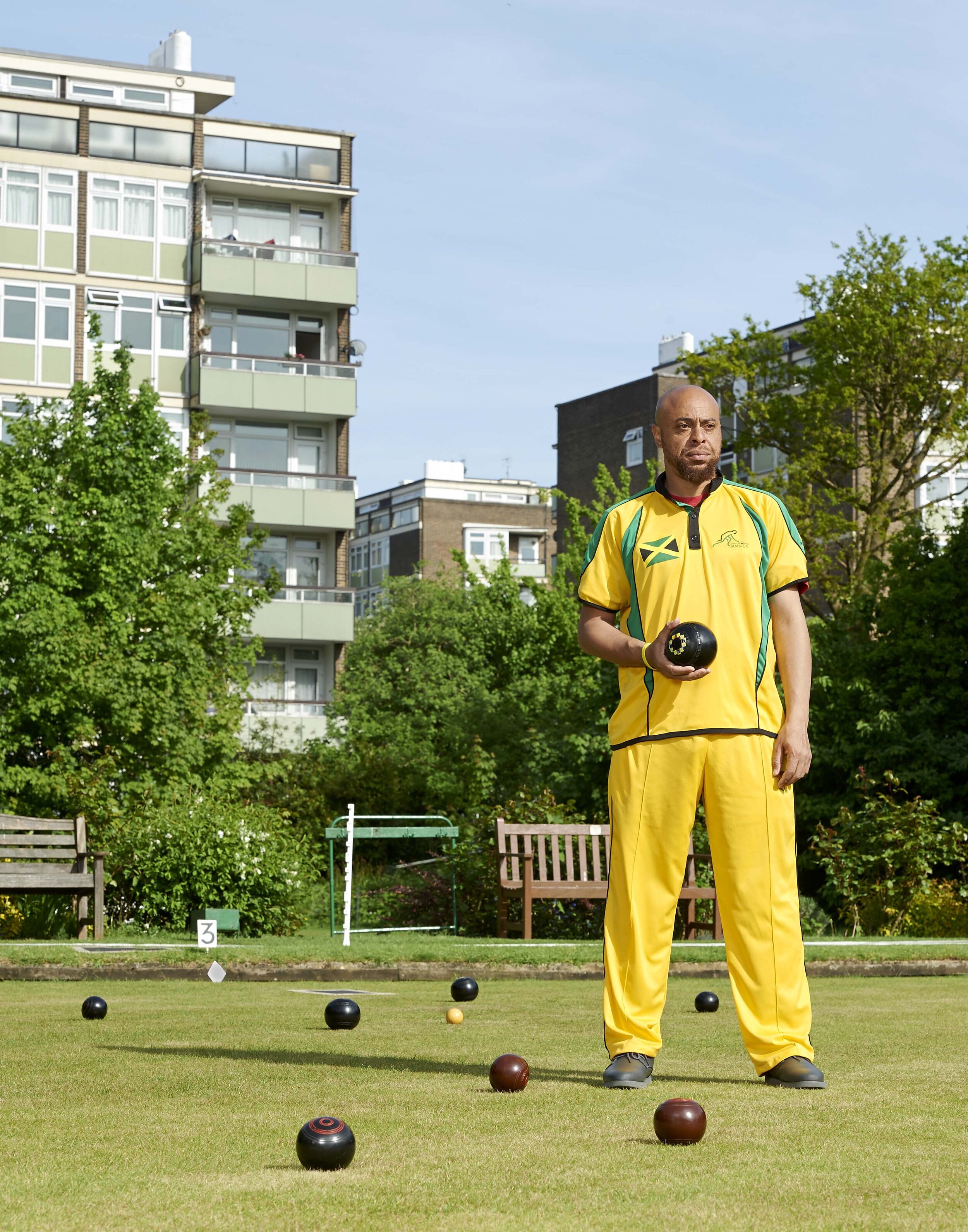 Man stands in a Jamaican sports outfit on bowling green 
