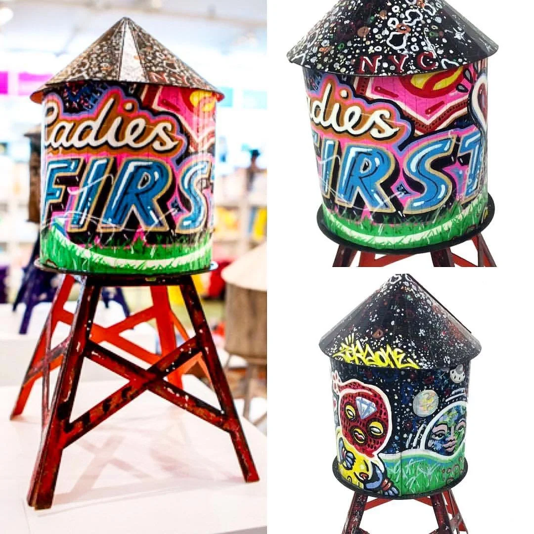Three colorful painted lanterns with different graffiti-style designs, placed on wooden stools with red legs.