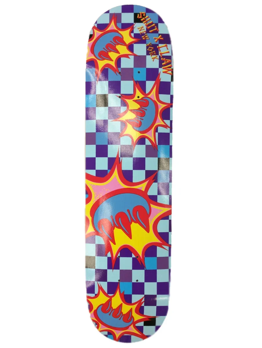 Colorful skateboard deck with a checkered background pattern in shades of purple and blue, decorated with comic-style explosion graphics and the phrase 'BOOM' in bold red and blue letters.