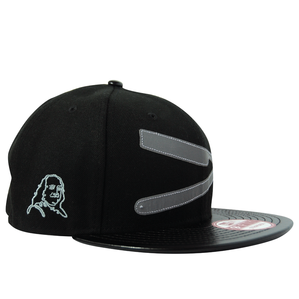 Black baseball cap with stitched gray stripes and a white embroidered image of a woman's face on the side, featuring a flat brim with a sticker.