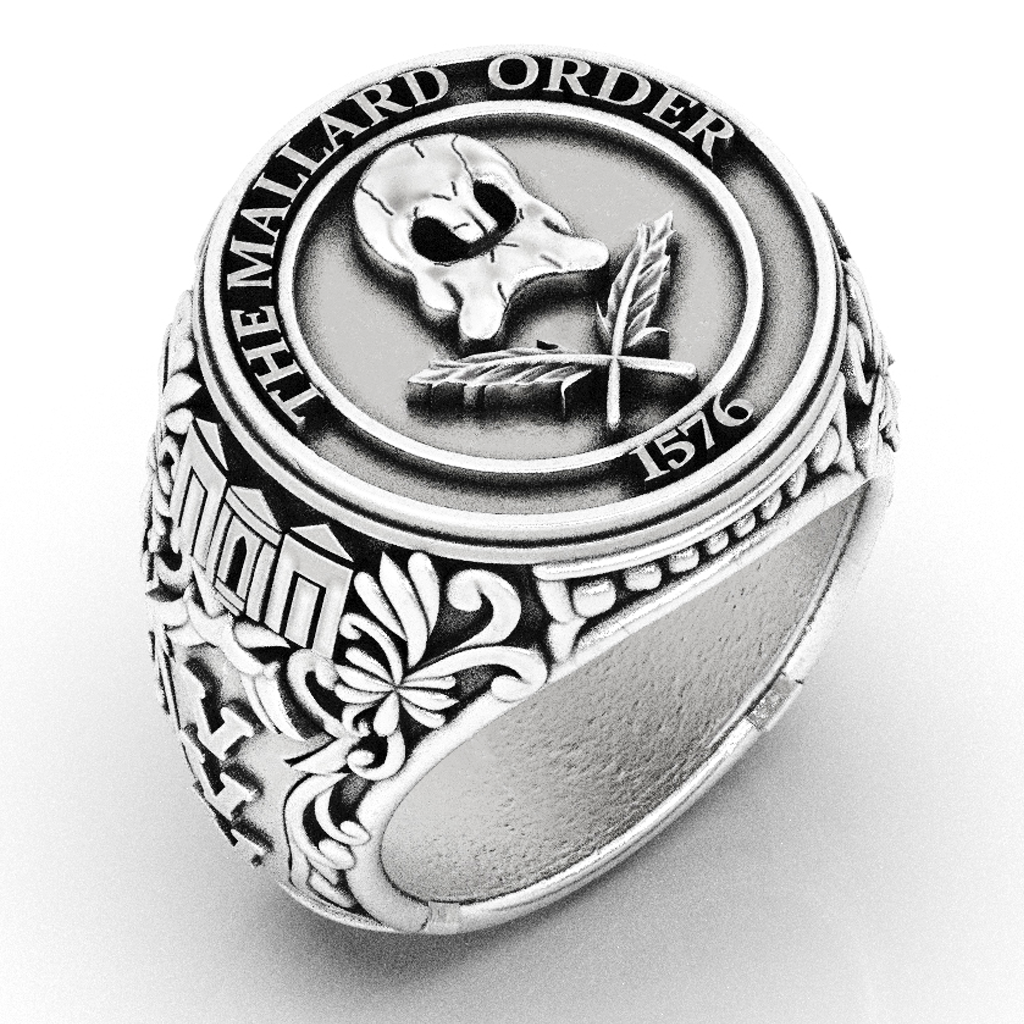 Black and white photo of a ring with a detailed design, featuring the text "The Mailard Order 1576" and a skull with an ornate pattern.