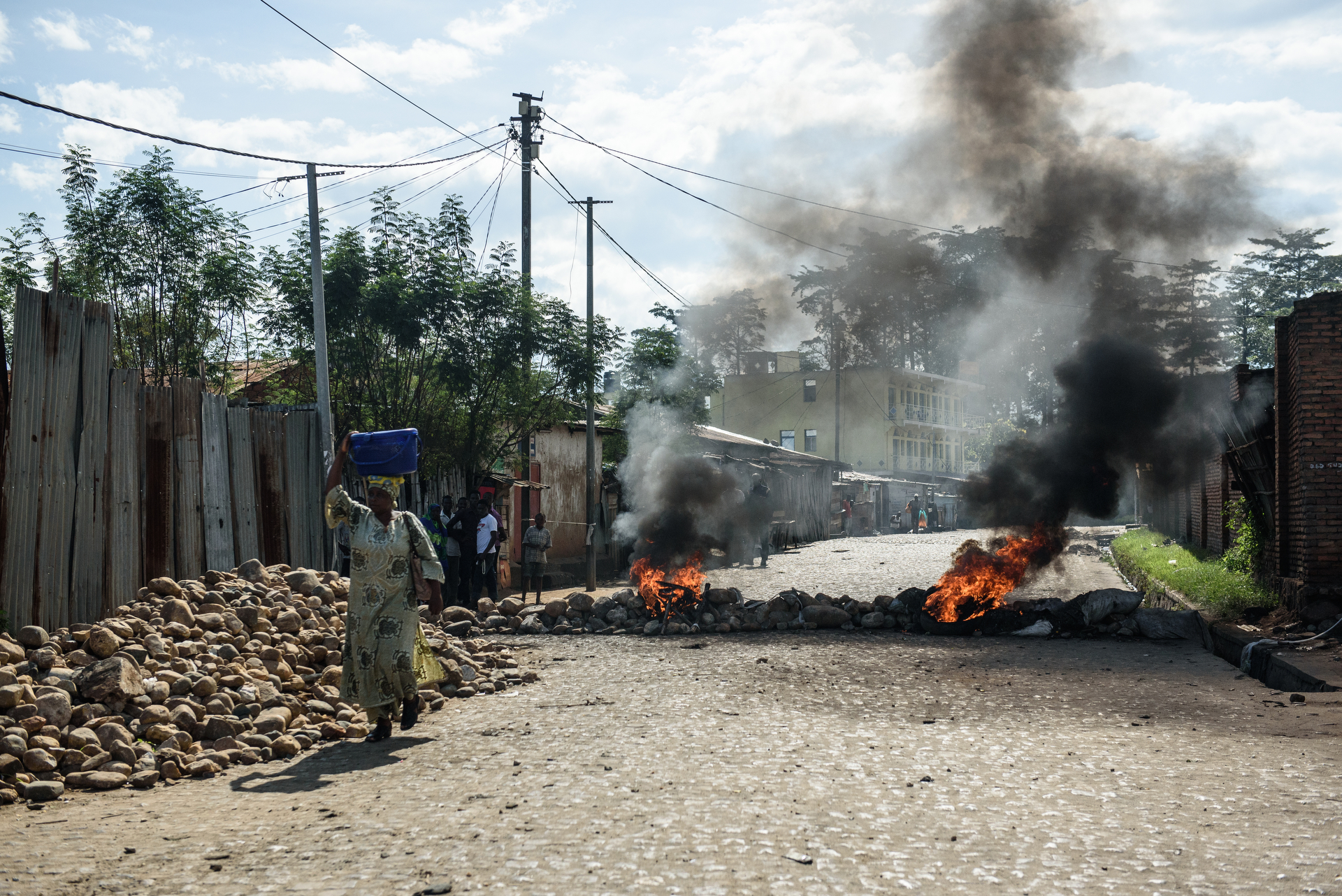  A woman carries a bundle past a barricade fire on a side street in Bujumbura, Burundi on 14 May. Following the 13 May announcement that president Nkurunziza was overthrown, putschistes and military fought over key locations such as the state broadca