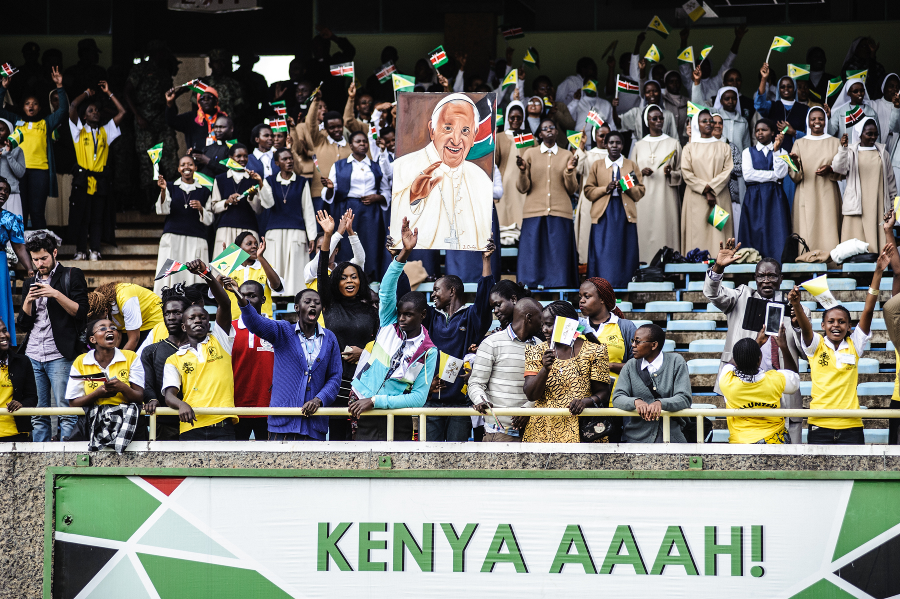  
Kenyan youth wave flags and cheer the arrival of Pope Francis at Kasarani stadium in Nairobi on 27 November 2015. The Pope spoke on the themes of tribalism, radicalization and corruption. Pope Francis is on a five-day visit to Kenya, Uganda and Cen