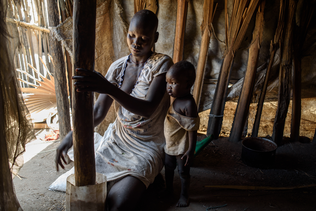  Nyaluide Machak, 25, grinds sorghum rations with a pestle on Nyoat island. 

 