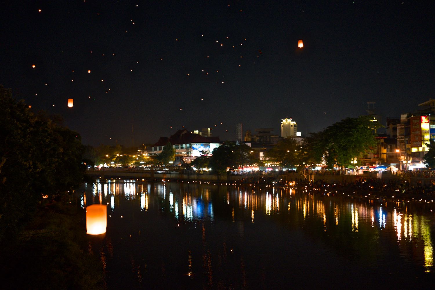 The river is lit up with Krathongs and the sky is filled with paper lanterns.