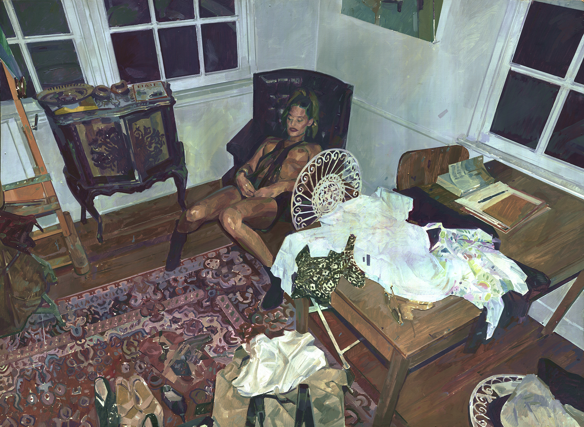 KAYLA OVER A BLACK CHARI OVER A ACARPET OVER A WOODEN FLOOR AND A BIT OF A MESS