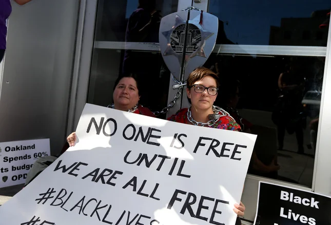 Corazon Amada, left, and Sarah Raridon, both of Oakland, chained themselves to the entrance to the Oakland Police Department along 7th Street in protest against police violence, in Oakland, Calif., on Thursday, July 21, 2016. (Anda Chu/Bay Area News Group)