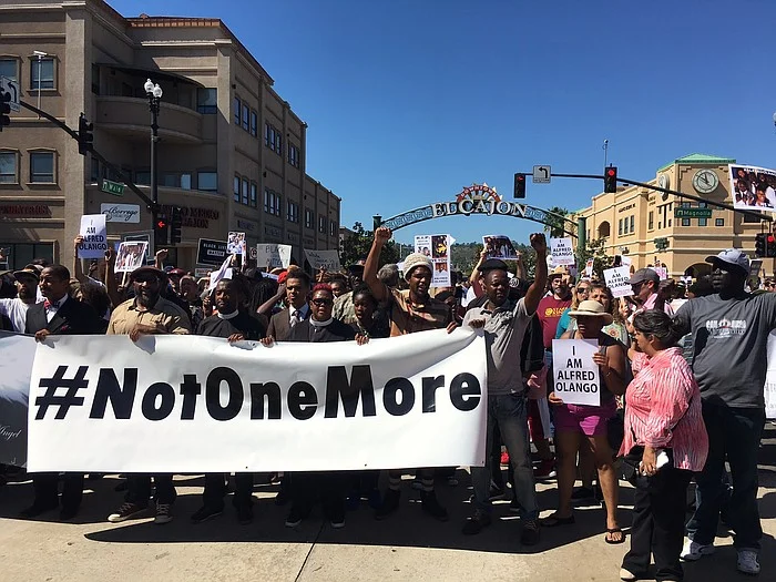 Above: A crowd of several hundred demonstrators march peacefully down Main Street in El Cajon, Oct. 1, 2016. They carry signs that read "Not One More" and "I Am Alfred Olango." Police officers fatally shot Olango, a Ugandan immigrant living in El Cajon, Sept. 27, 2016. (Kris Arciaga/KPBS)