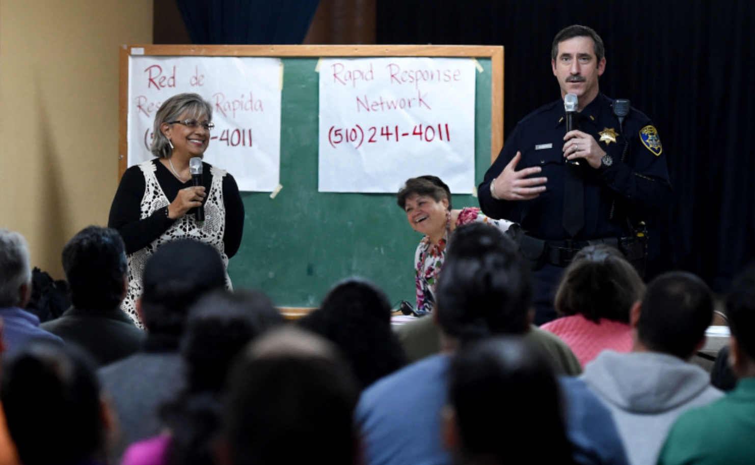 Mike Reilly, a lieutenant with the Oakland Police Department, draws smiles from certified court interpreter Elizabeth Dantes, of Napa, left, and Emma Paulino, of Oakland Community Organizations, when he tells the group of mostly hispanic individuals that it makes him nervous too when he sees a police officer while he speaks at St. Jarlath Catholic Church in Oakland, Calif., on Sunday, March 19, 2017. (Susan Tripp Pollard/Bay Area News Group)