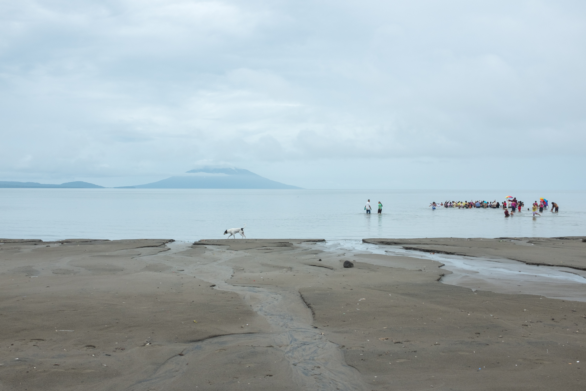  A babtism on the shores of Lake Nicaragua with the twin peaks of Ometepe Island in the distance near Rivas, Nicaragua 