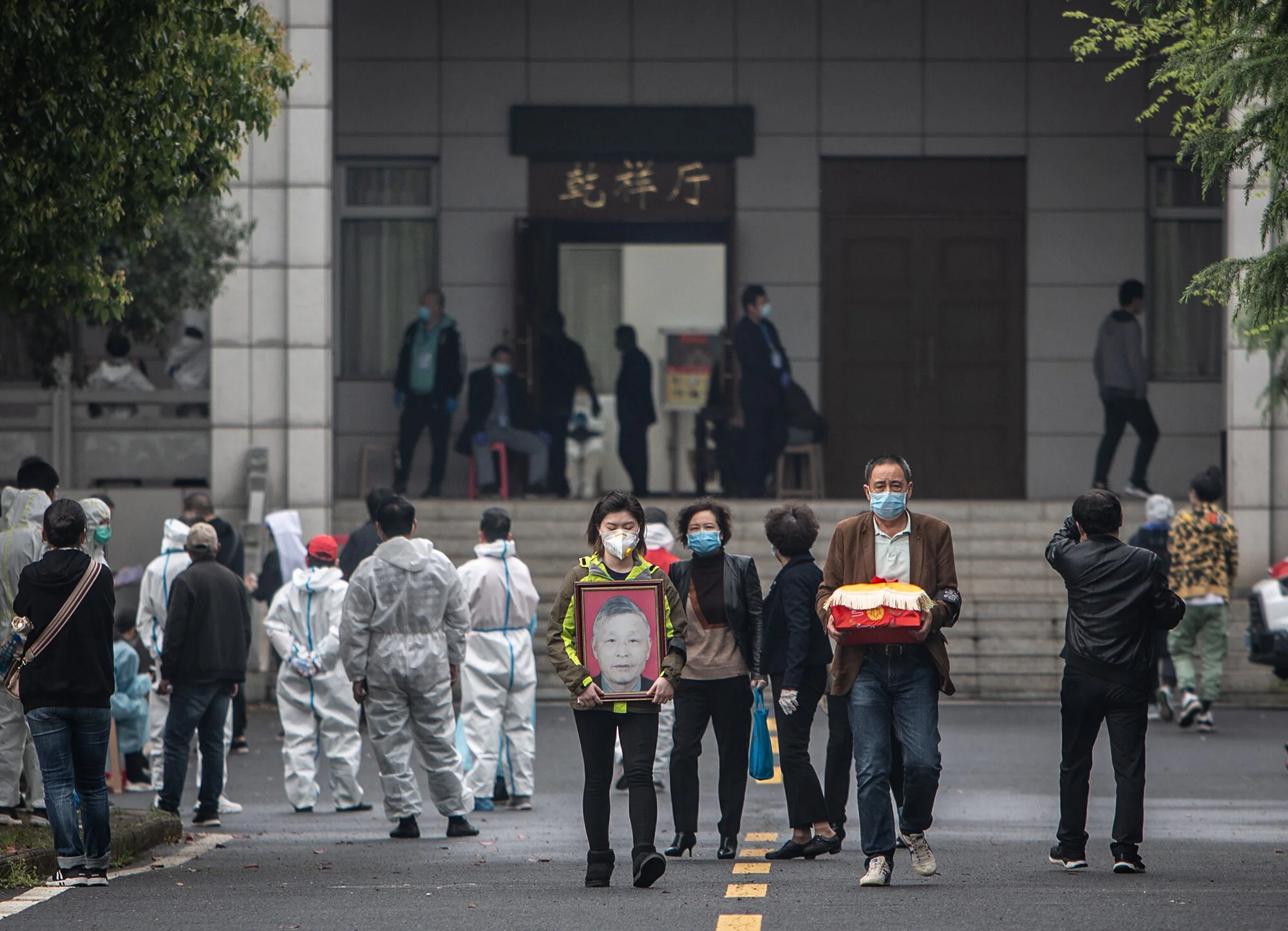 3月26日早，武汉市汉口区殡仪馆静园楼，领到逝者骨灰的家属捧着骨灰盒和遗像准备离开。该殡仪馆于3月23日开始发放新冠疫情期间逝者骨灰，家属接到社区通知后，通过社区预约或前来现场排队领取。工作人员介绍，无预约现场排队取灰，可能需要等候4小时以上。李峥苨:摄.jpg