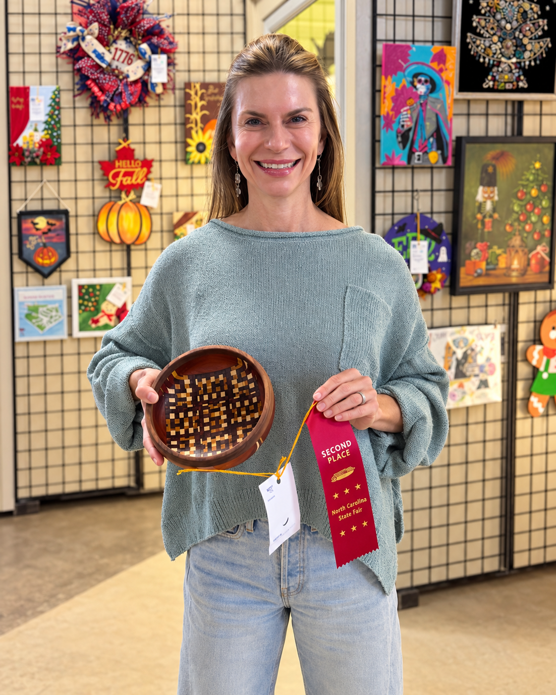 Rebekah Gunn smiling at the State Fair while holding her patterned woodturned bowl and second-place ribbon.