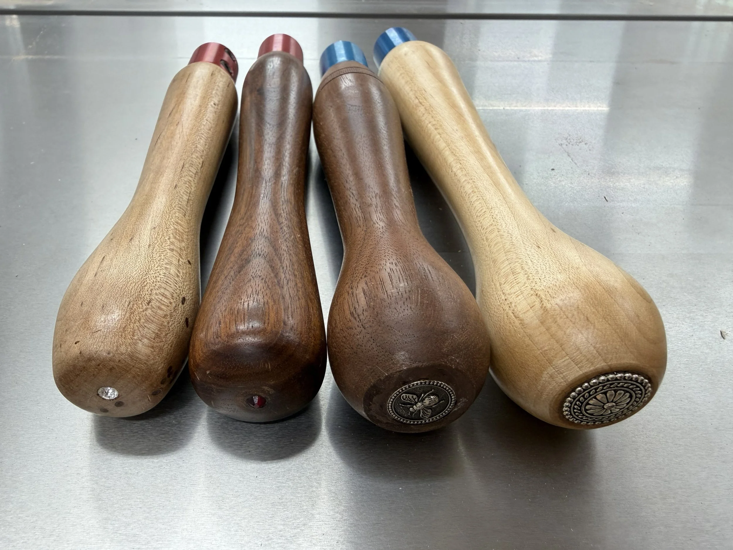 Several handmade woodturning tool handles made by Rebekah Gunn, including handles embellished with small personal decorative details.