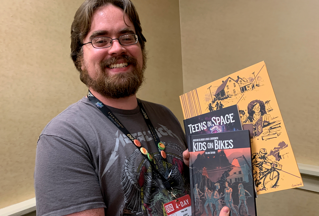 A happy gamer with their copy of Teens in Space and Kids on Bikes