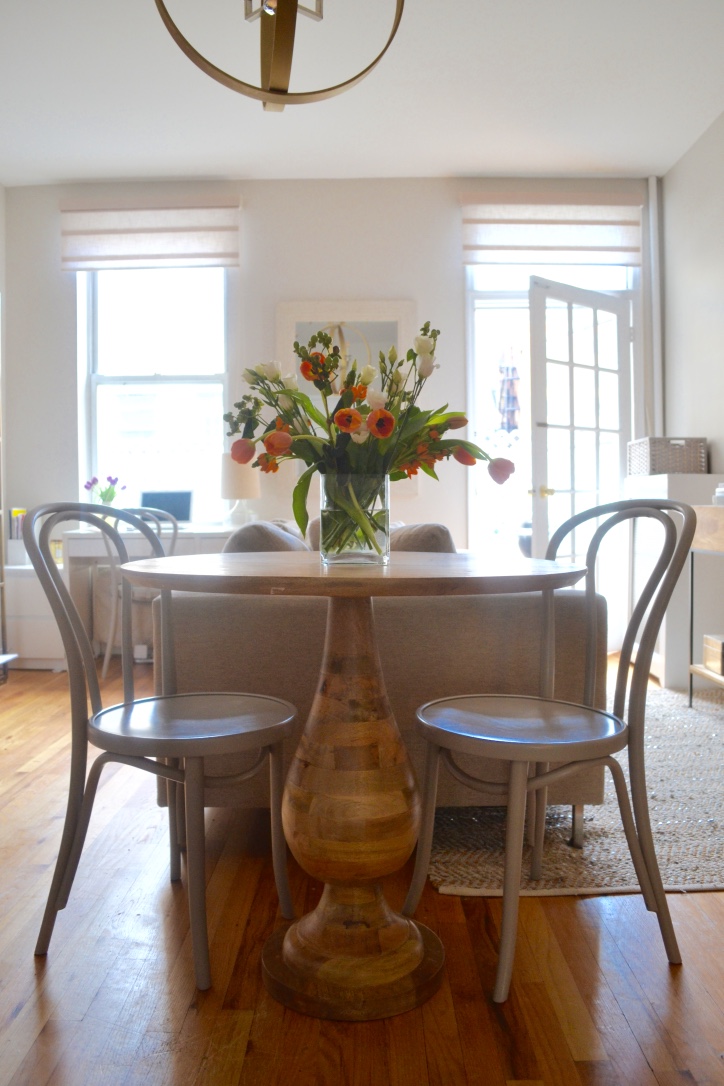 A small rustic bistro pedestal table acts as a side table to the sofa and the dove grey Thonet style chairs also make it a functional dining table.