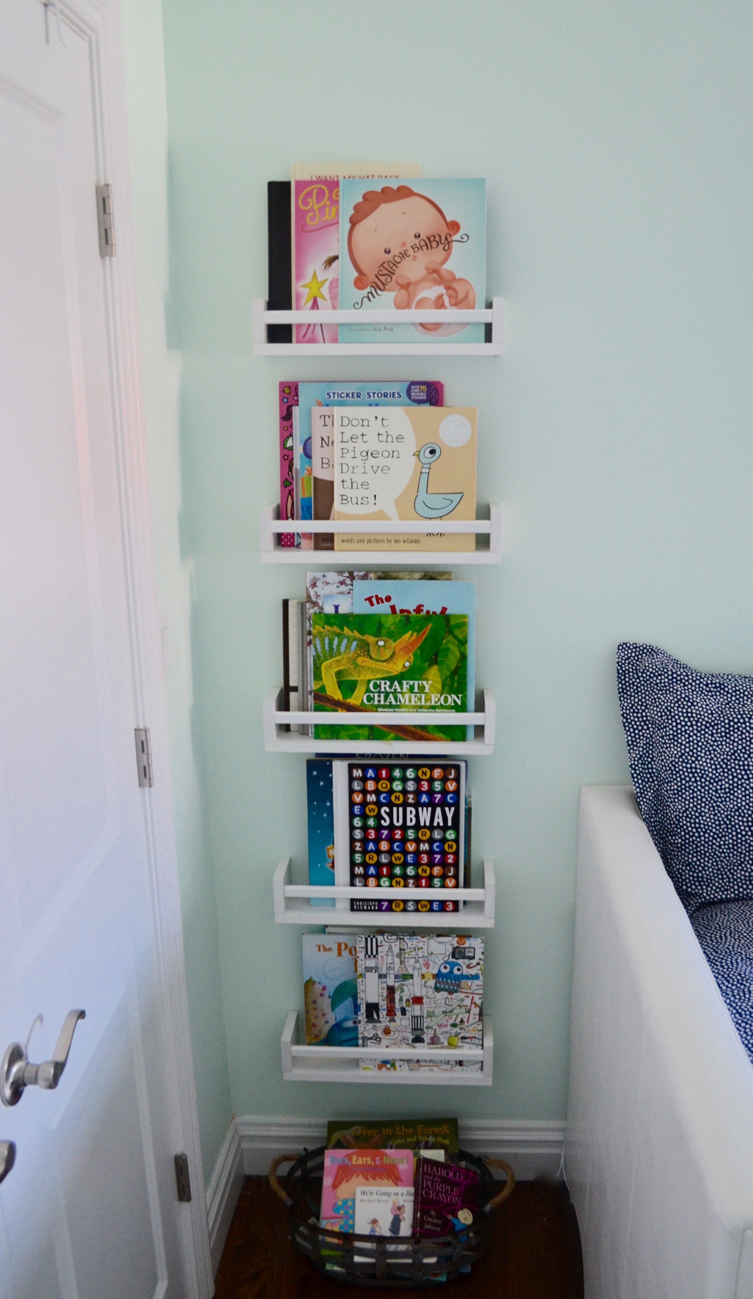 Client M is quite the little bookworm, so book storage was a priority. Wall-mounted shelves, bins and baskets for overflow did the trick.