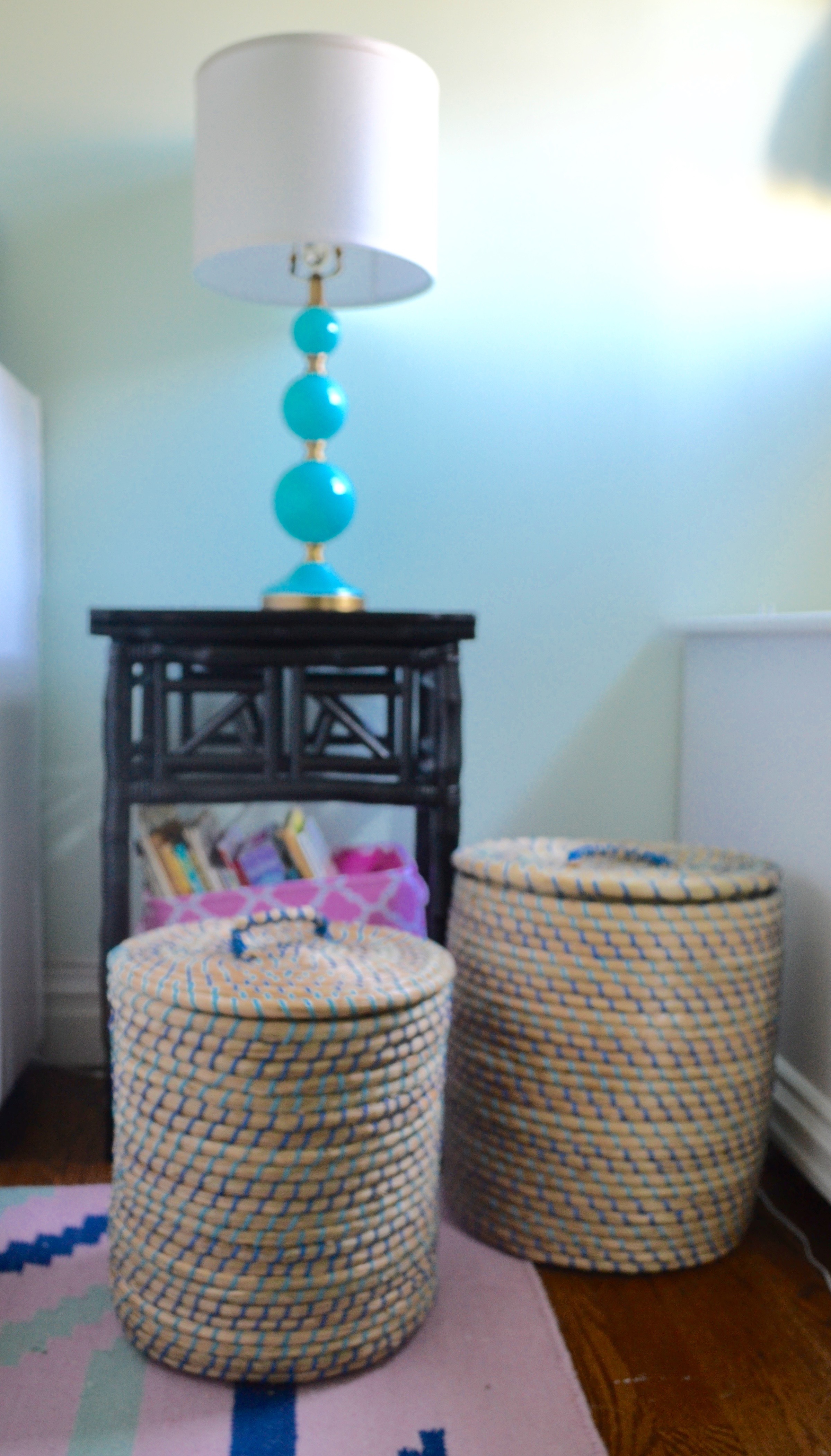 A nightstand houses a canvas bin full of books, and Moroccan style storage baskets with lids corral Client M's extensive stuffed animal collection.