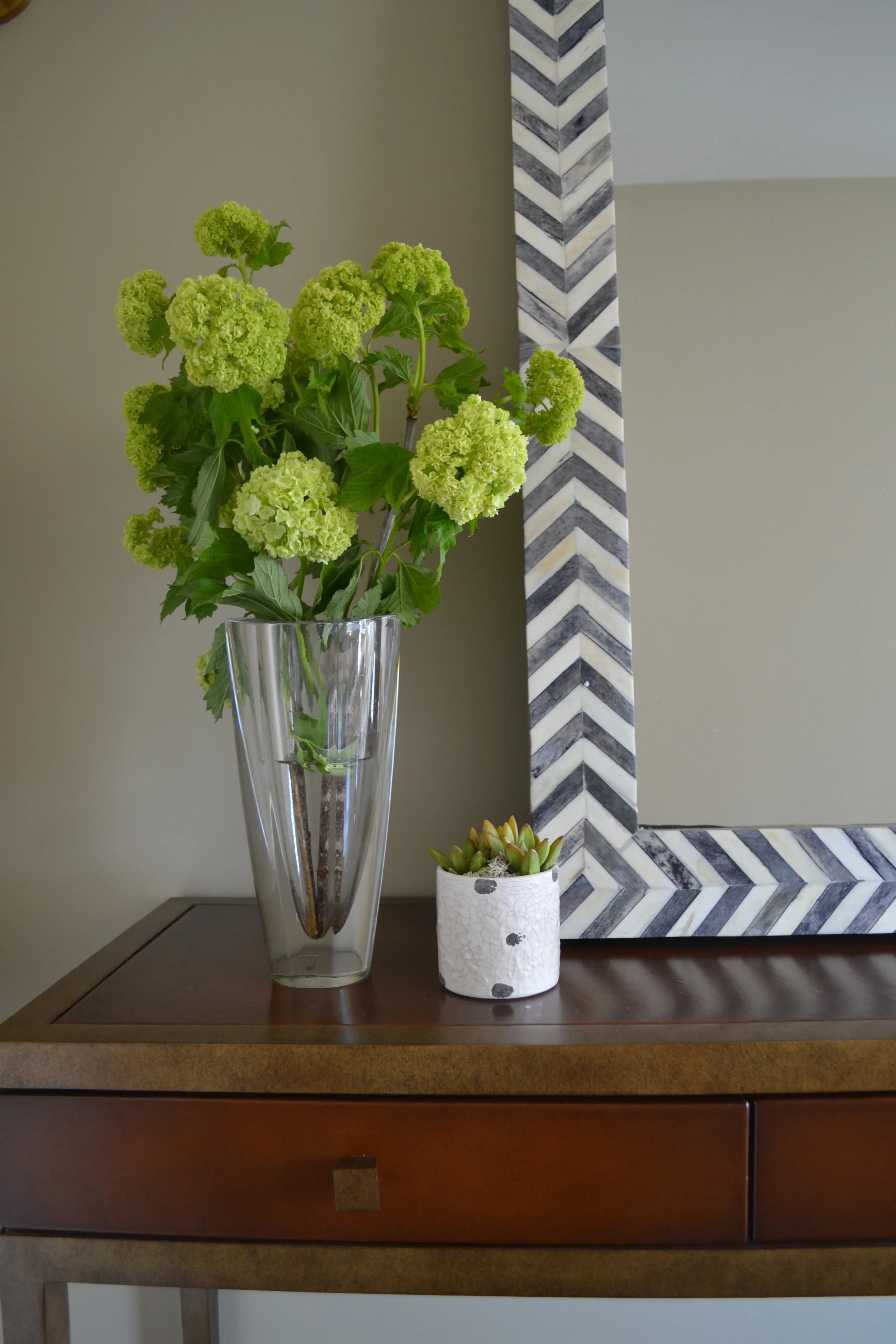 A "skinny" yet functional console table in a warm leather sits in the entry. The drawers add function and the space beneath is perfect for storing bags and shoes upon arrival.