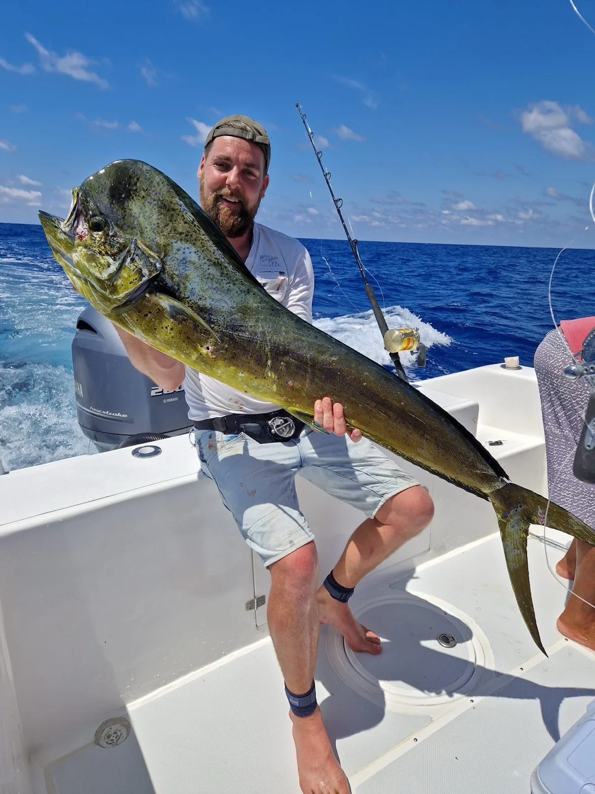 Man holding a large fish on a boat in the ocean during daytime.