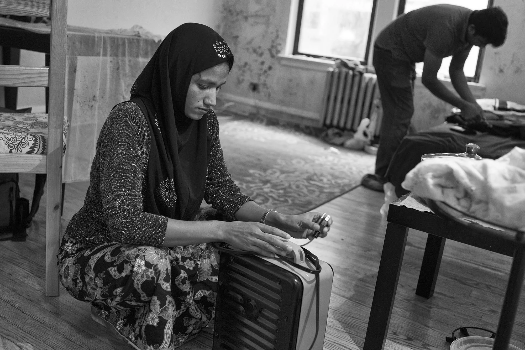 Laila sets up a space heater in her new living room. She has never experienced a winter before. "There was no one listening in Burma," said Laila in an interview before the Rohingya crises escalated into, what the many have called, a genocide.