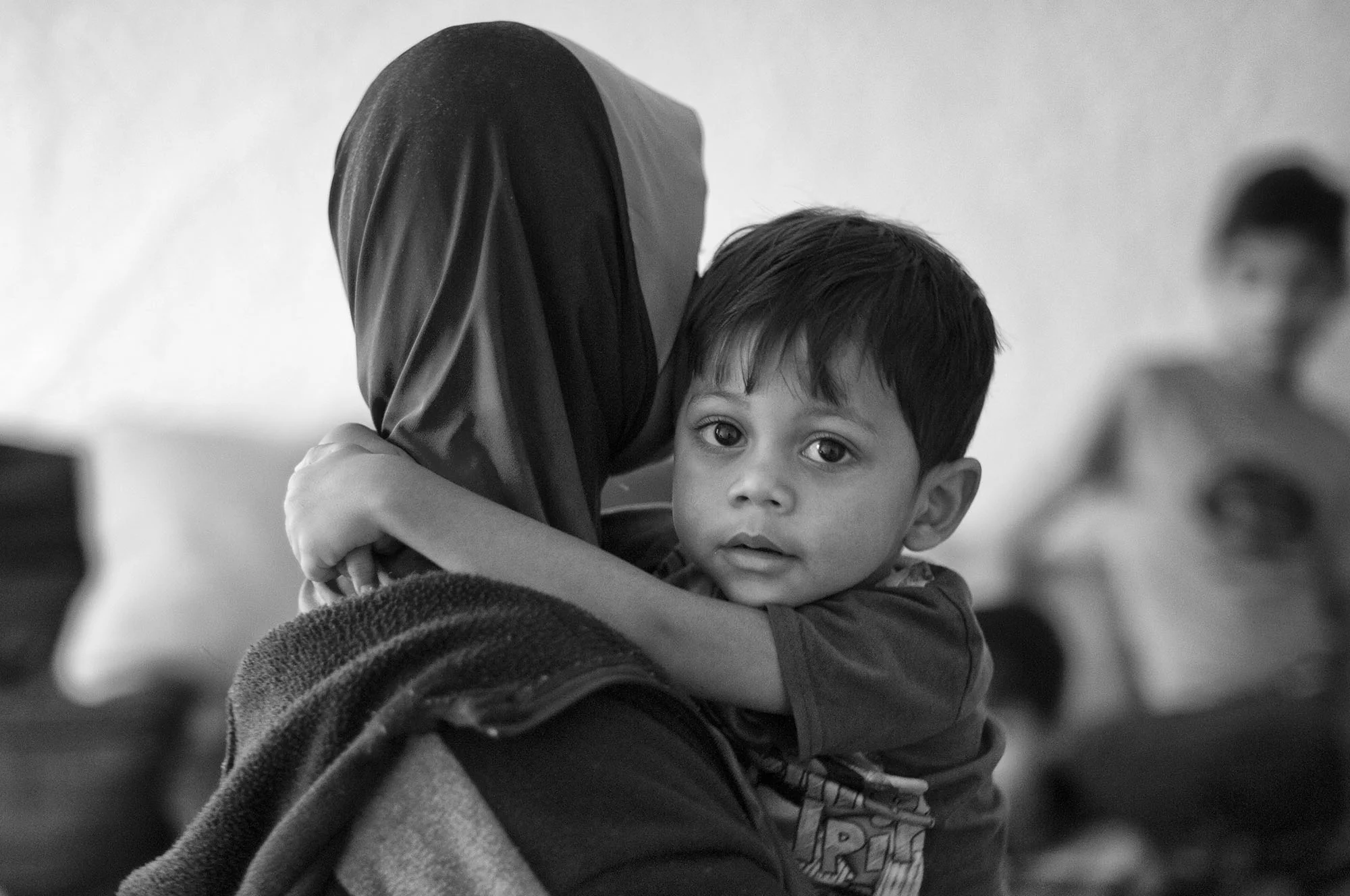 Mohammed Sultan, a three-year-old Rohingya boy, clings to his mother in a neighbor's home. Mohammed was born in a refugee camp in Bangladesh. 