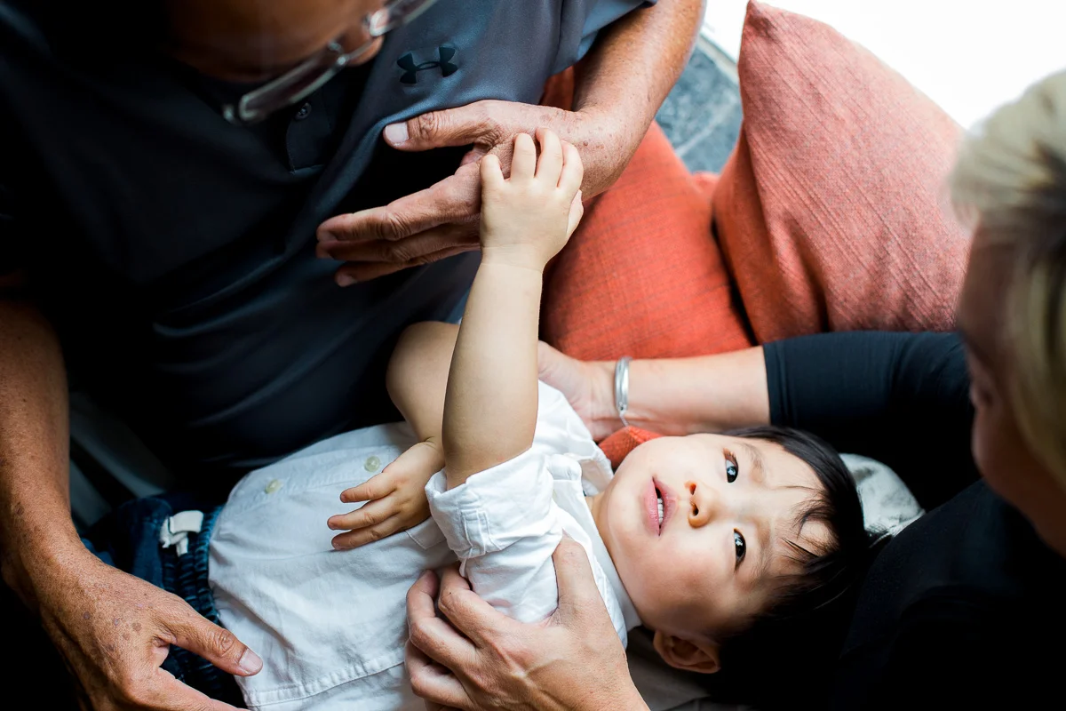 Grandparents embrace a young boy who looks up into his grandmother’s eyes during a family photoshoot in Kuala Lumpur.