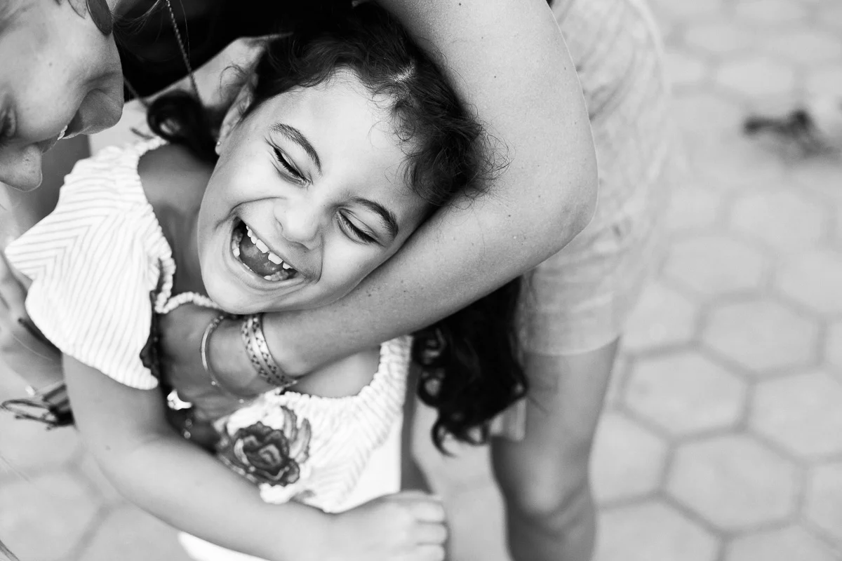 A black and white image of a mother tickling her daughter by family photographer Erica Knecht in Kuala Lumpur.