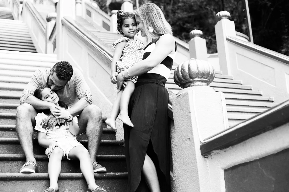 A black and white family portrait with a mother and father each embracing a daughter in Kuala Lumpur by Erica Knecht.