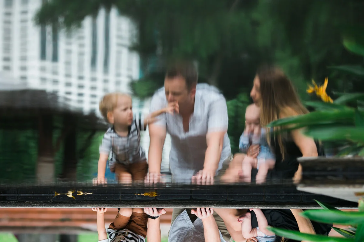 A family . photography session in KLCC park featuring a family reflected in a pool of water by top Asia family photographer Erica Knecht.