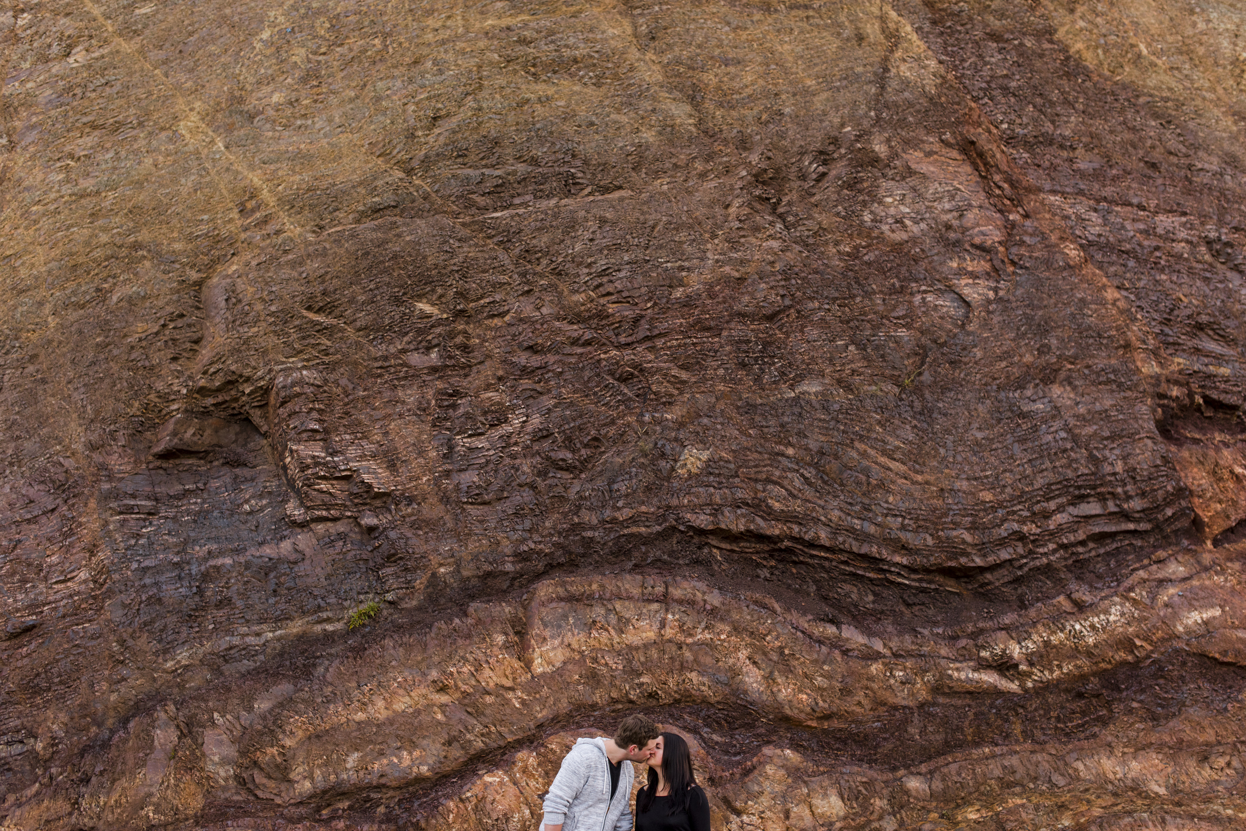 couple kissing in front of rocks