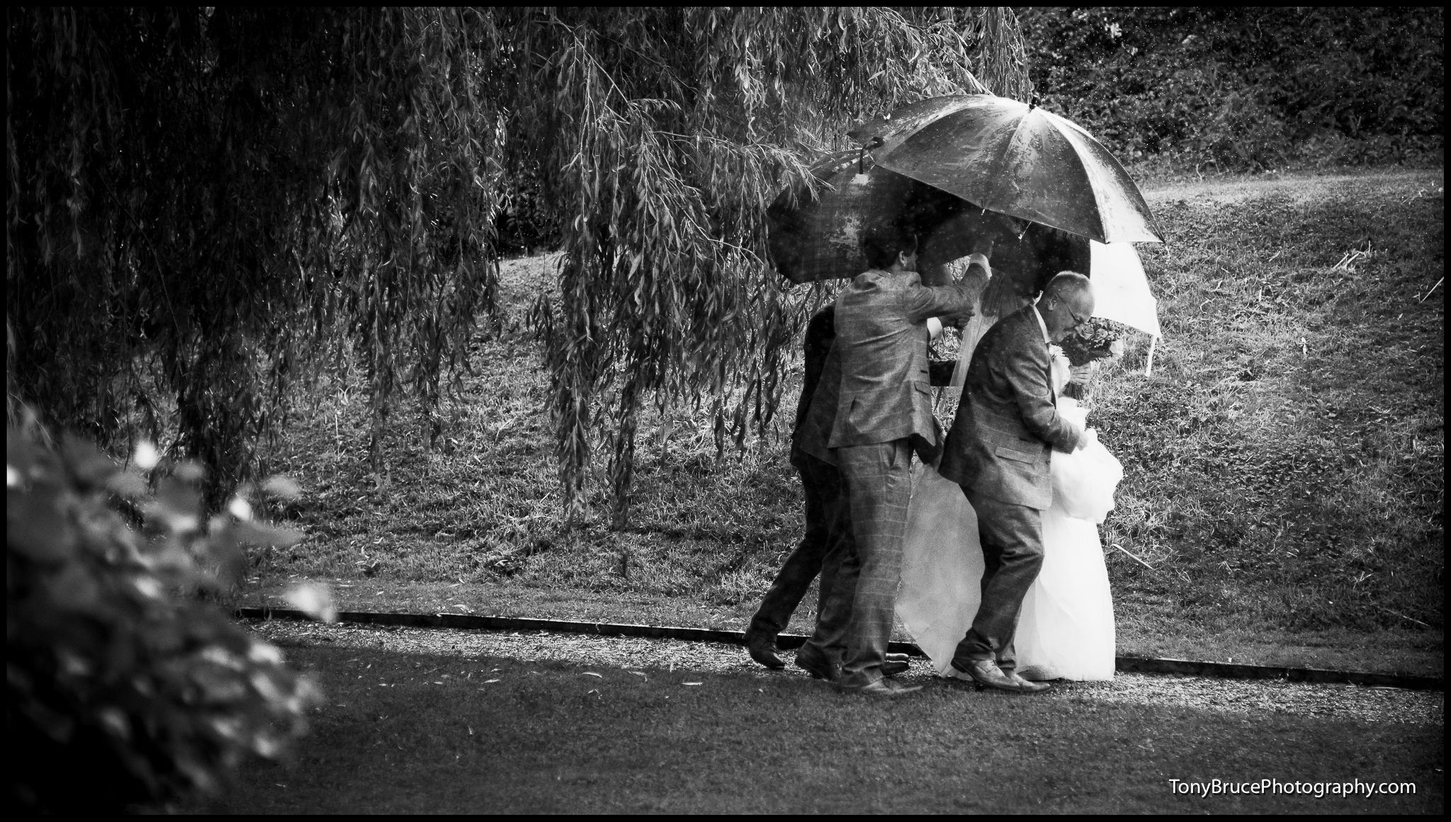 The Bride is protected from the driving rain.