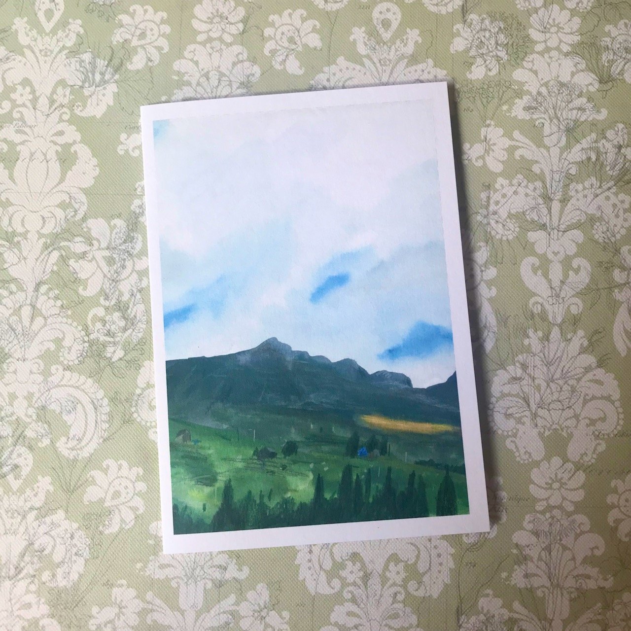A landscape of mountains, blue sky beneath the clouds and grasslands at the foot of the mountains