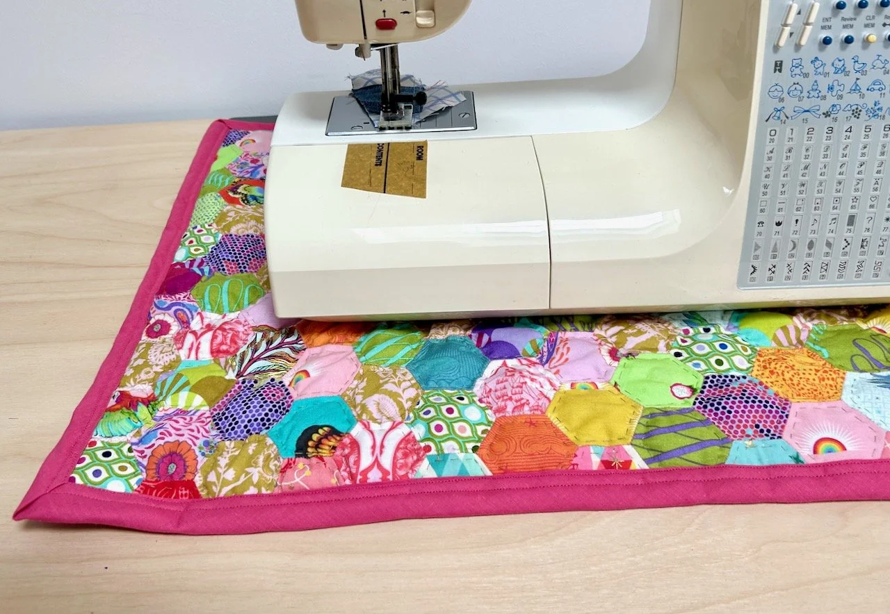 The finished mat edged in raspberry bias binding on my desk, complete with sewing machine