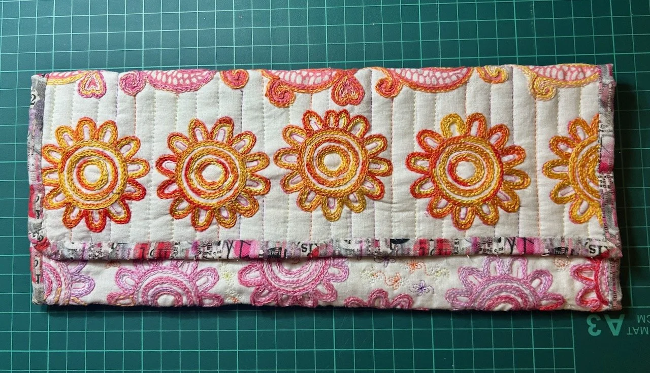 The finished pouch - folded into three and with the lining used as binding.  A curved corner on the left and a square corner on the right intentionally.
