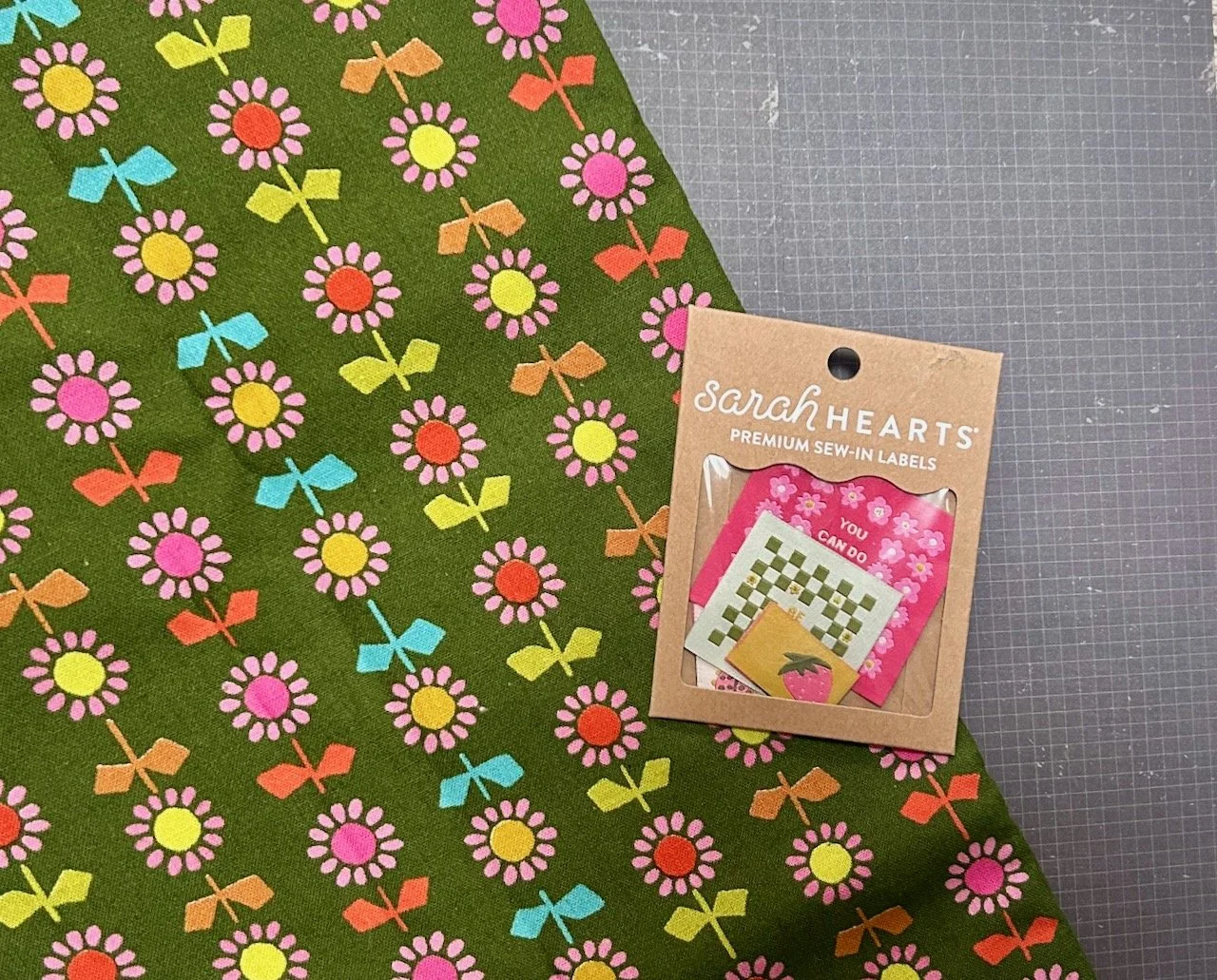 The green background striped daisy print with a pack of sarah hearts labels on top