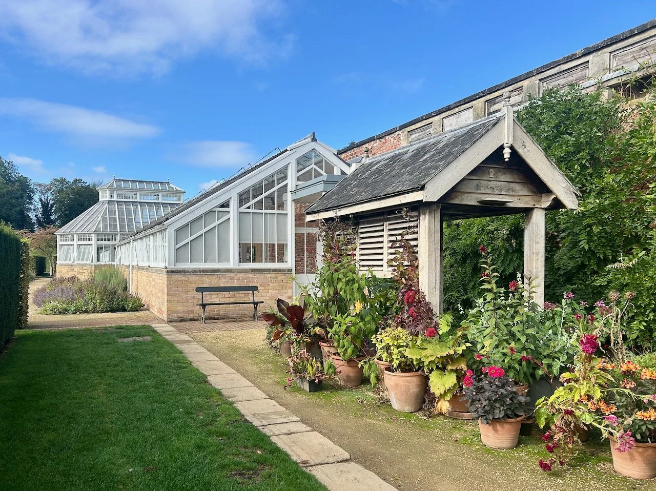 The greenhouse is in the background, in the foreground there's an array of pots with a shelter behind