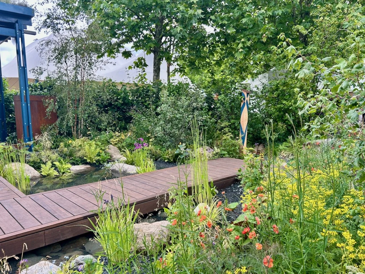 The boardwalk extends out through the planting to an upright wooden sculpture