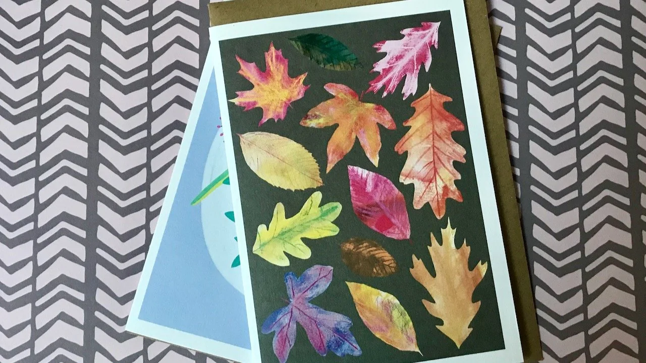 Green, red, amber and purple autumn leaves on a brown background, with the previous card beneath