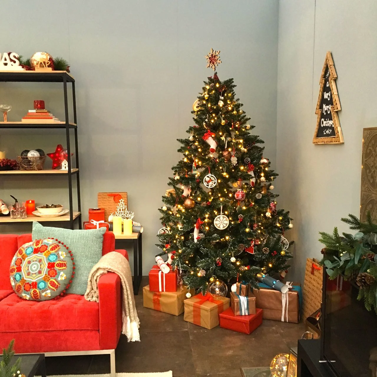 A tree and a berry red sofa in this folklore themed room set at the Ideal Home Show at Christmas
