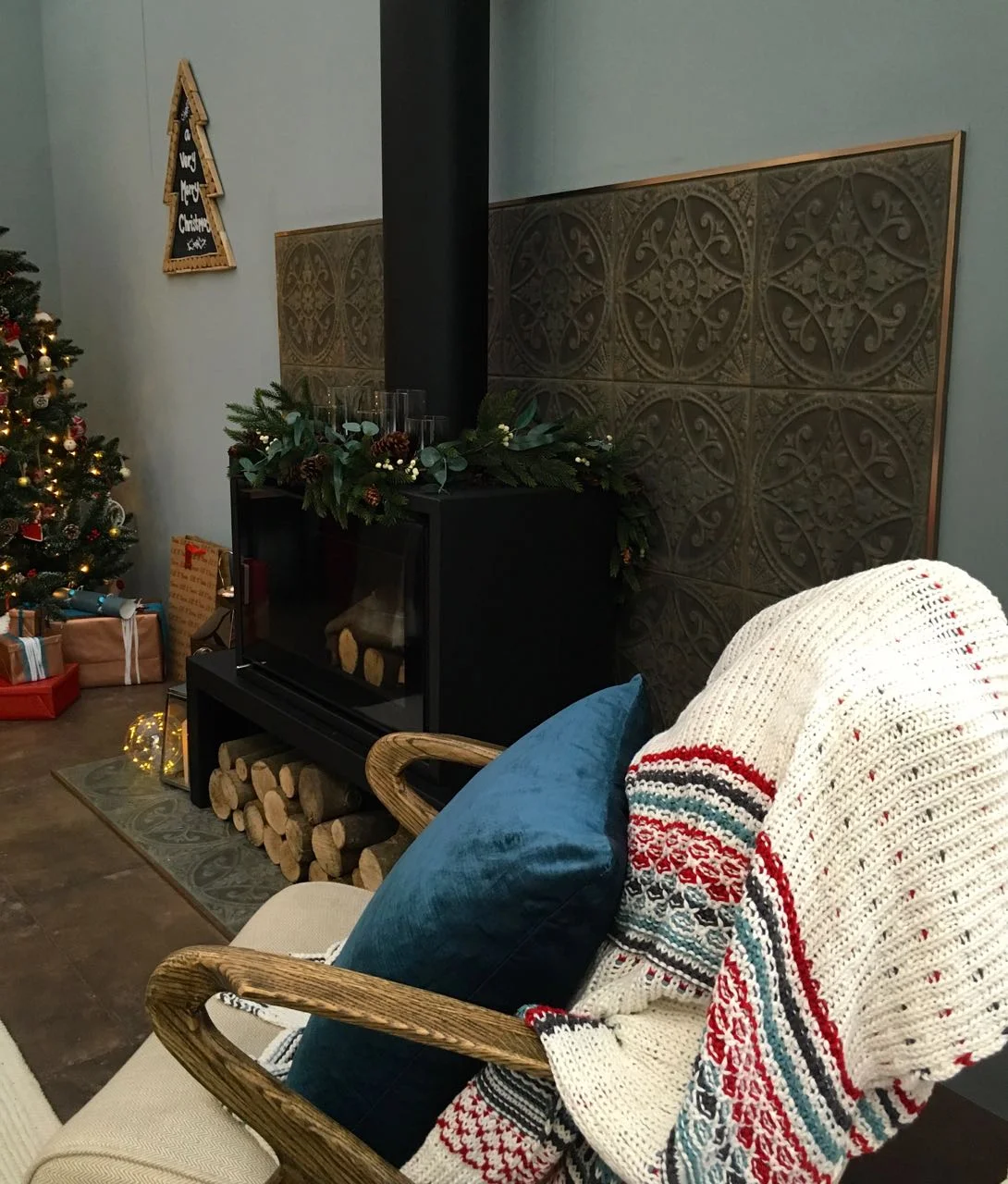 A cosy armchair in front of the wood burner  in this room set at the Ideal Home Show at Christmas
