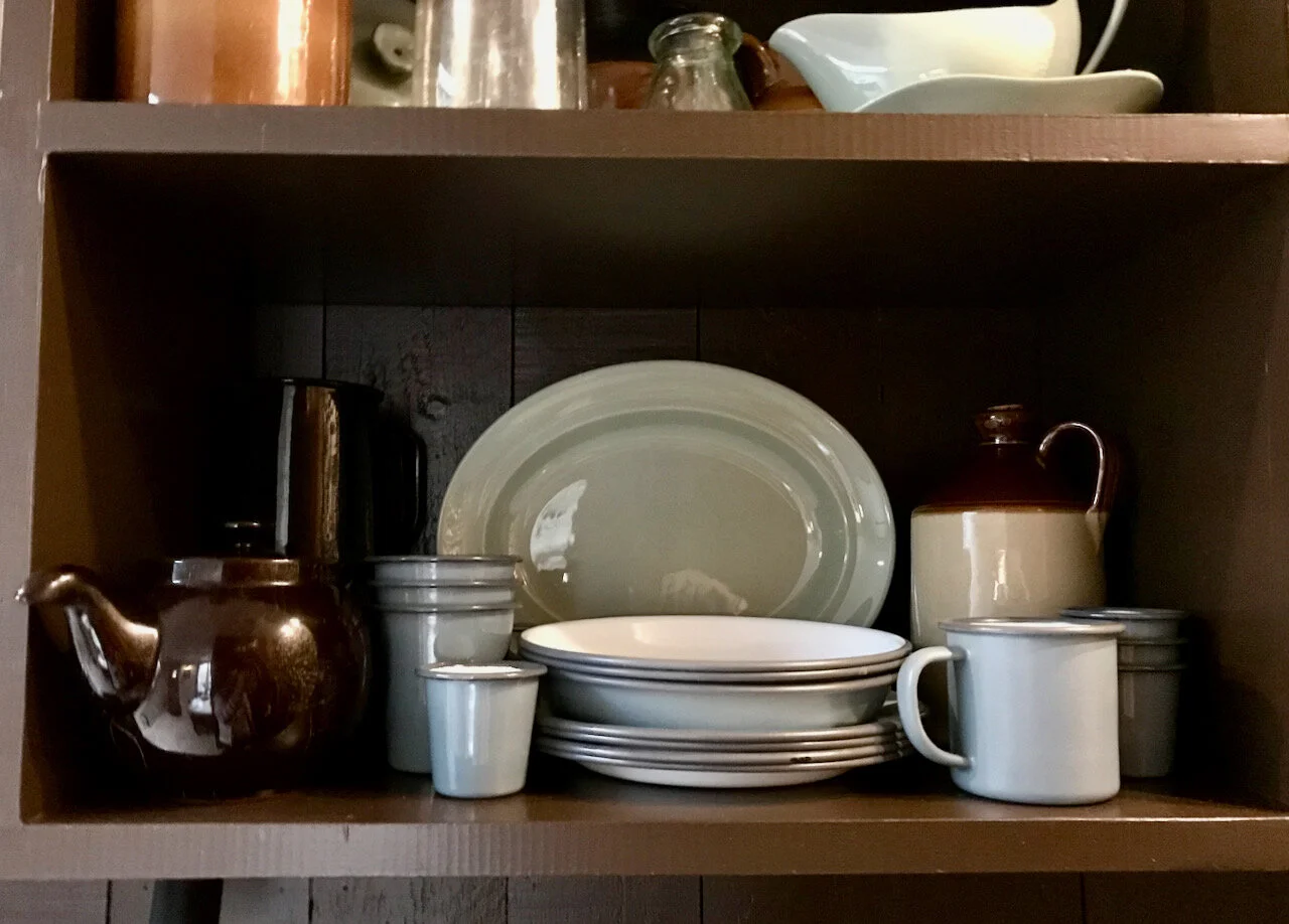 teapot, stack of plates and enamel mugs