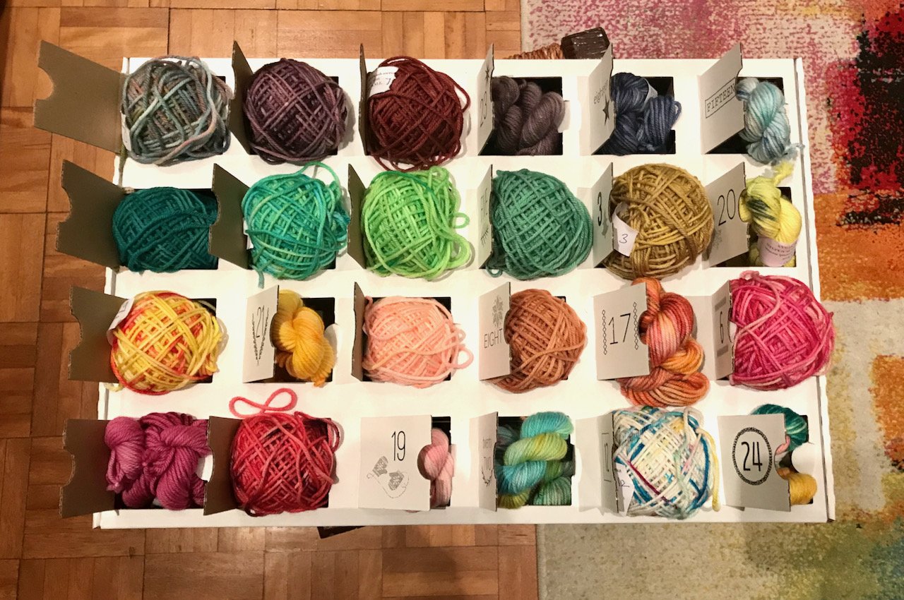 Overhead of my yarn advent box, with over half of the skeins wound into balls