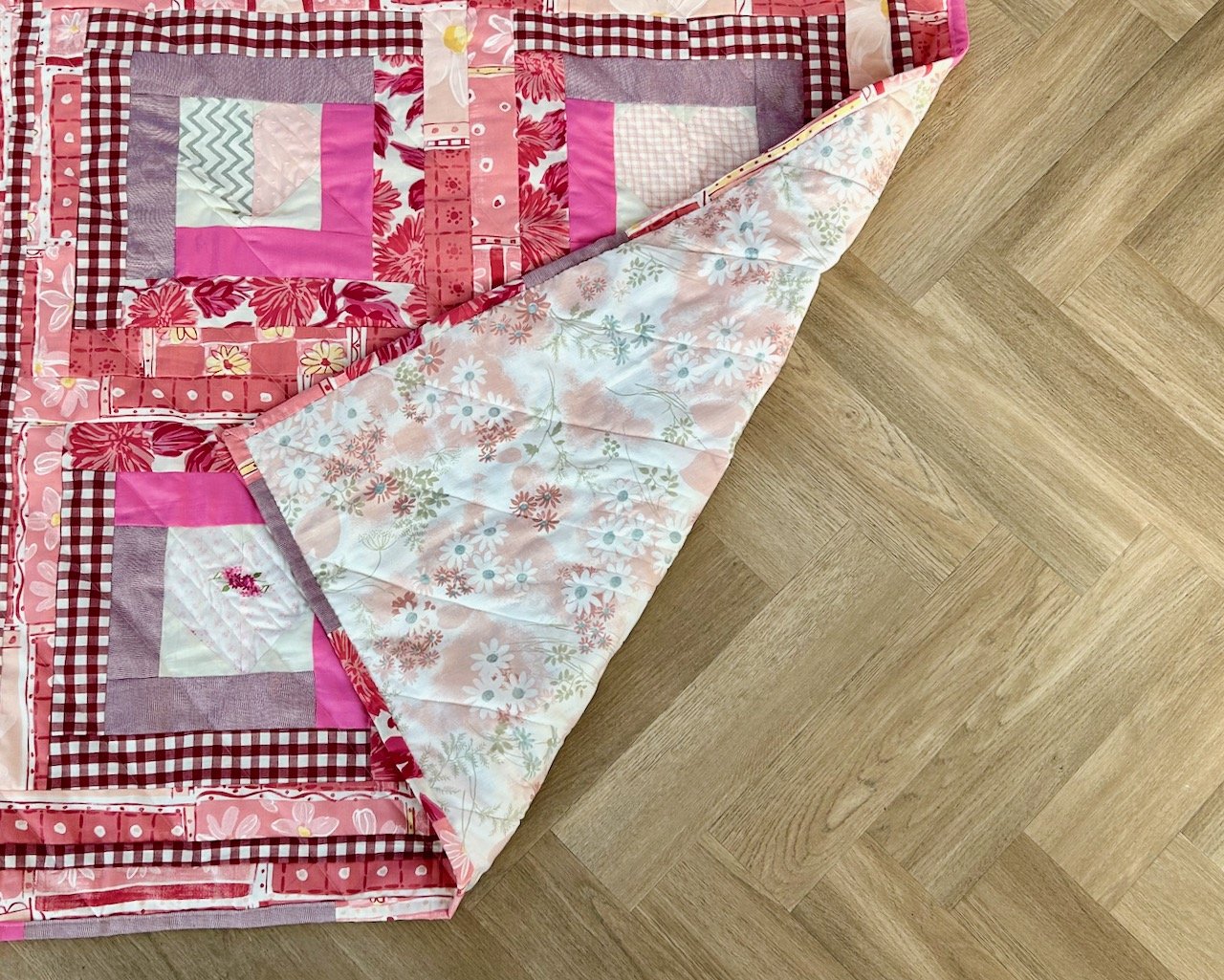 The finished quilt this time with the bottom right hand corner turned back on itself to show the bagain backing fabric