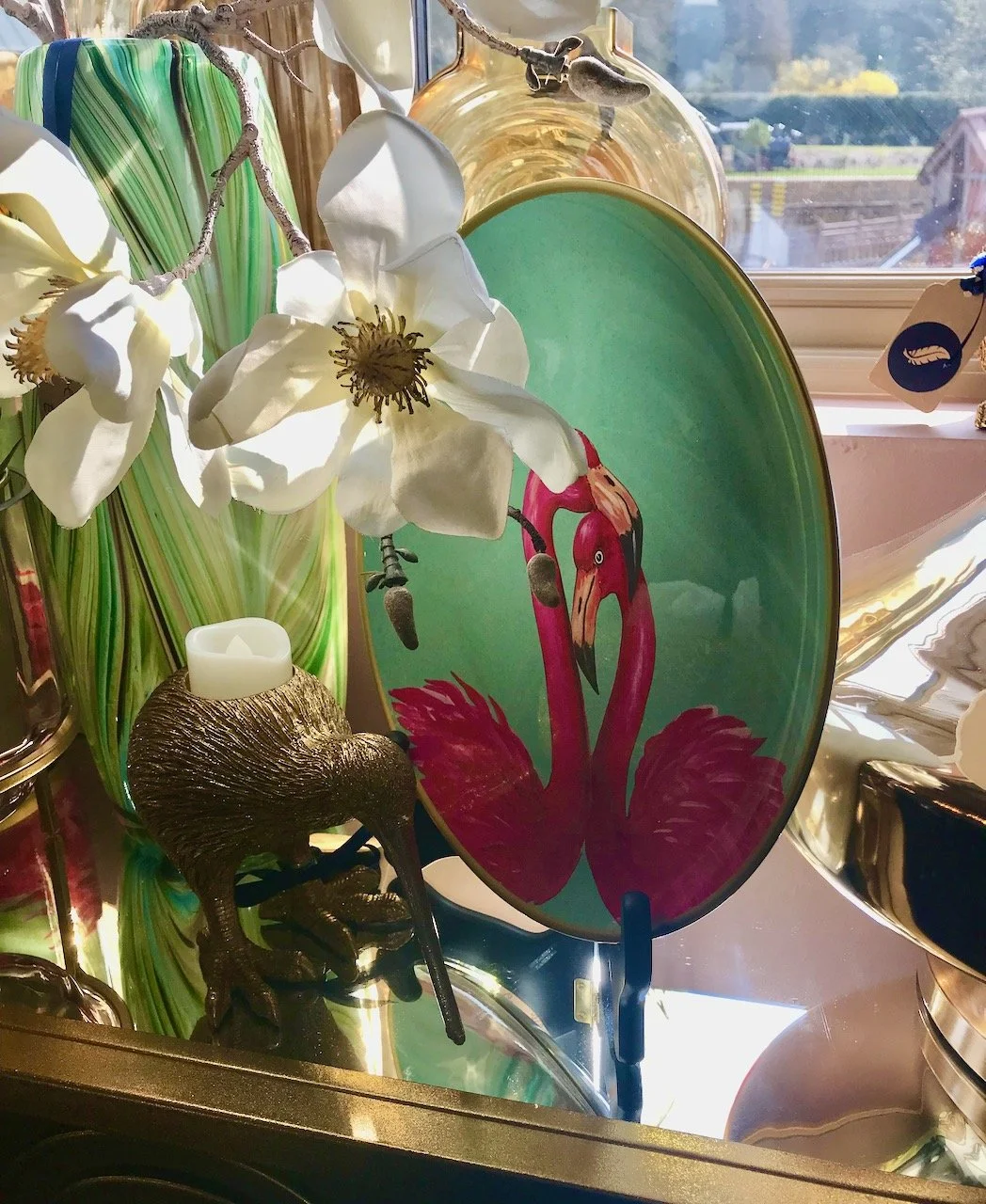 A green plate with two flamingos alongside white orchids