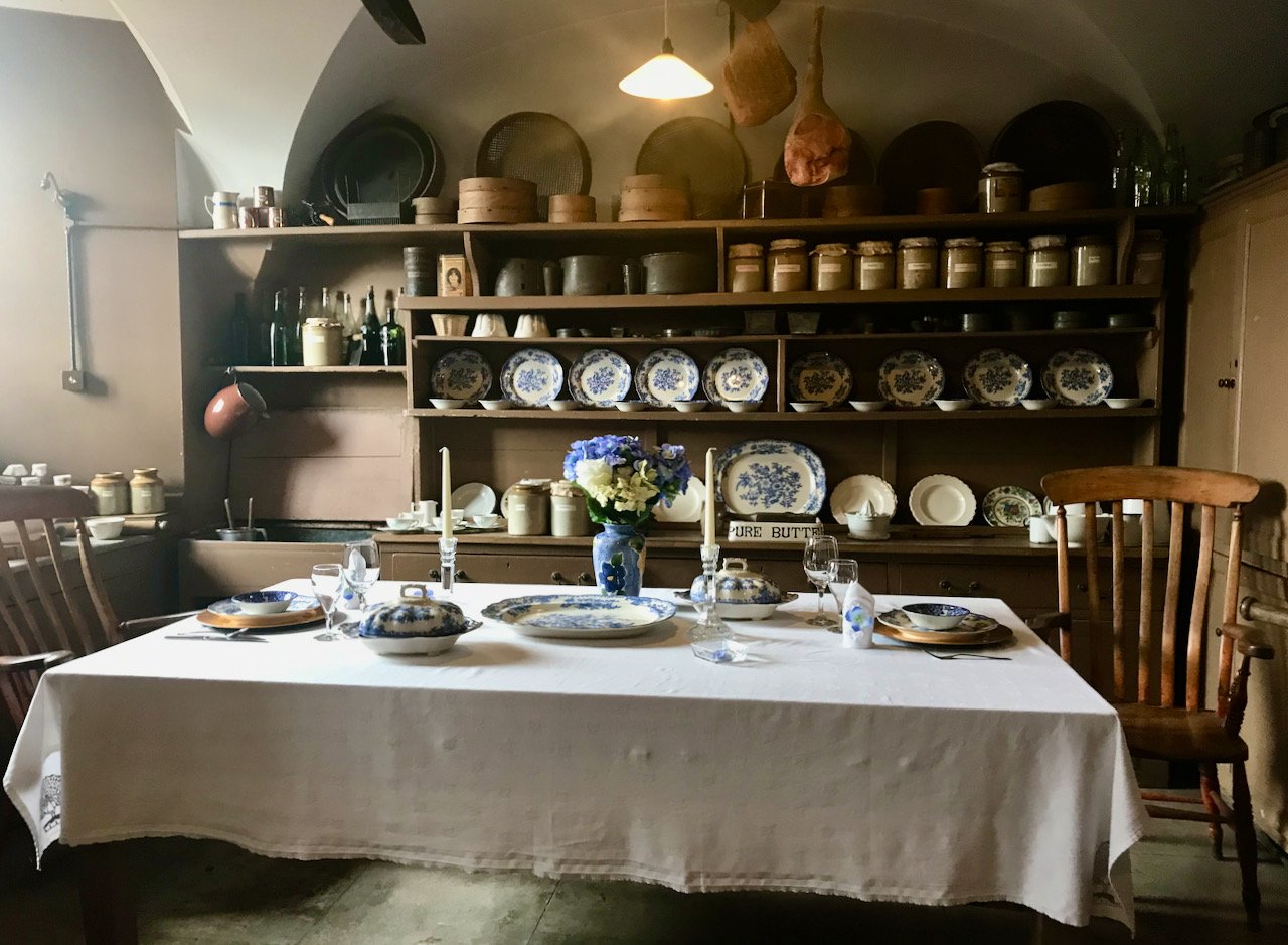 a separate side room with a table laid with blue/white crockery.  A dresser in the background with more crockery, storage jars and bottles