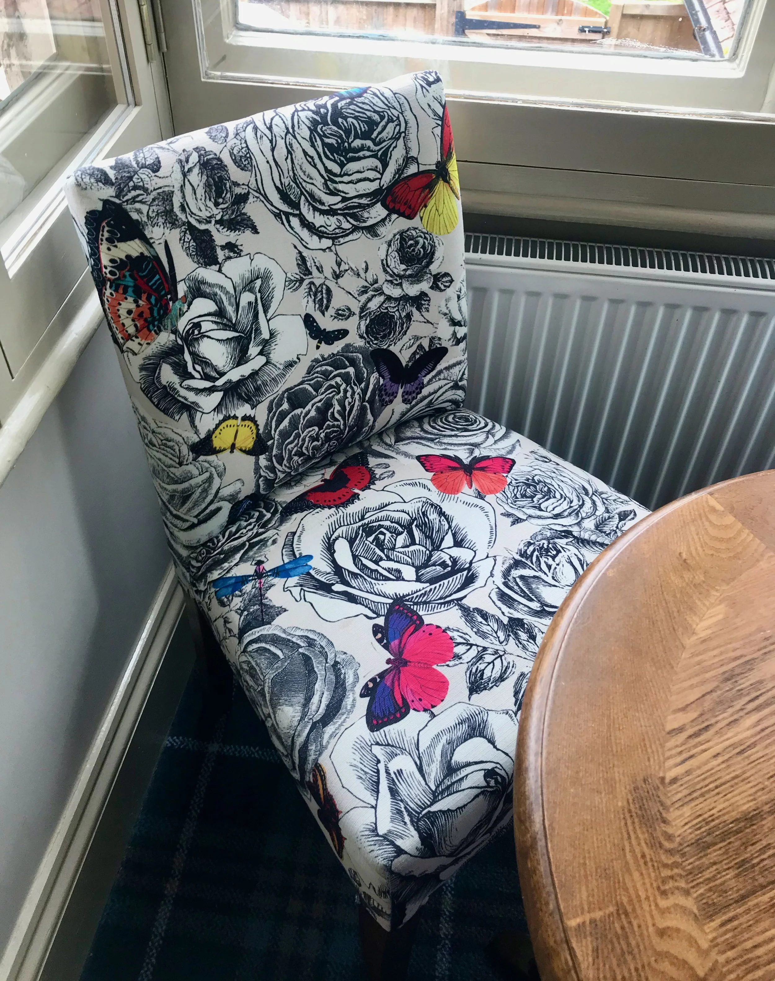 A chair covered in black and white material with pops of colour for the butterflies