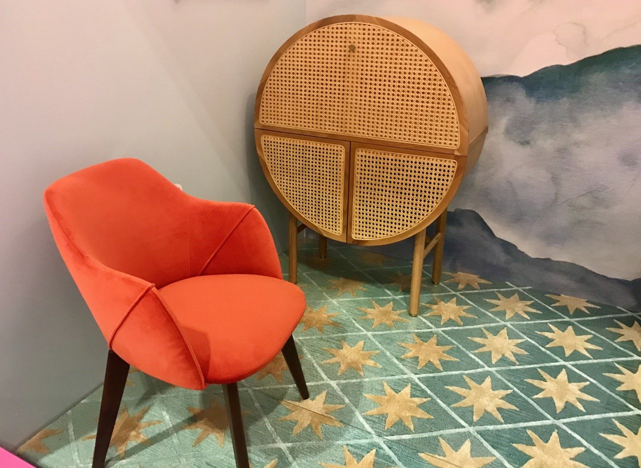 The round wicker 'desk' cabinet, orange chair on a rug which is a green/blue with gold stars