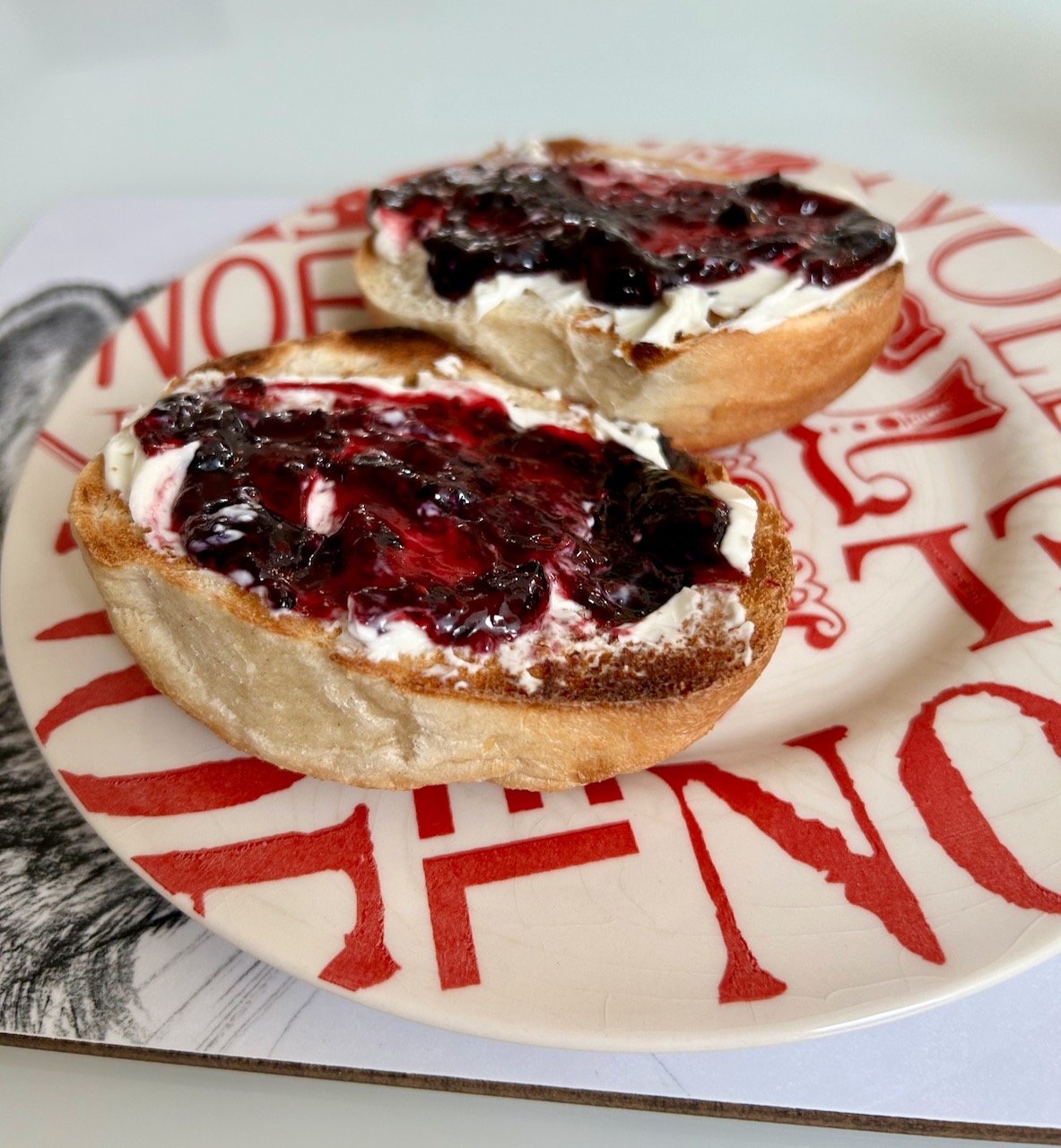 A bagel cut in half with each half topped with cream cheese and homemade blackberry & lime jam - yum!