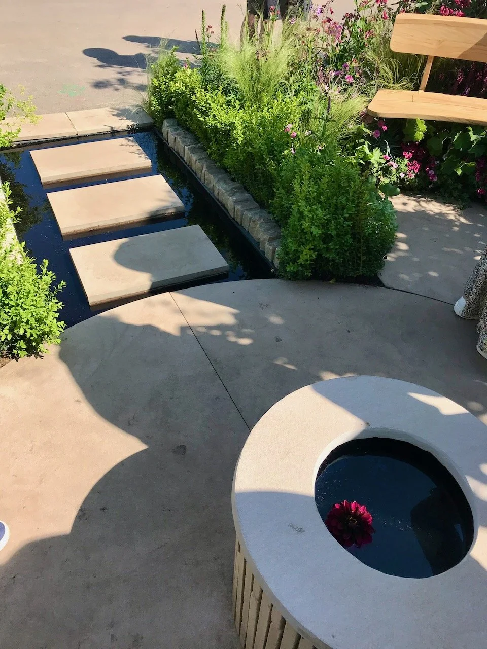 entry and exit to the garden is across three calm stepping stones surrounded by water and edged with small box plants, the centre section of the garden is also paved with a raised central area